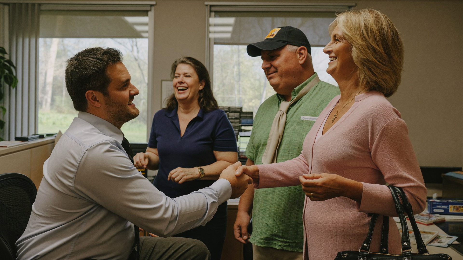 Advisor shaking hands with an older client in the Kelmeg & Associates office