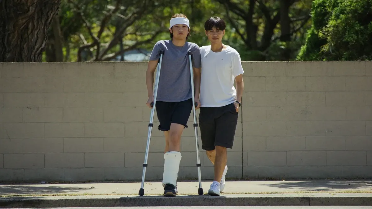A teenager on crutches with a leg cast walking with a parent