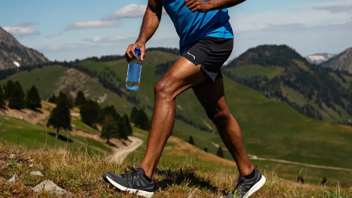 A healthy man in his fifties hiking in the Colorado foothills, trail running shoes and water bottle