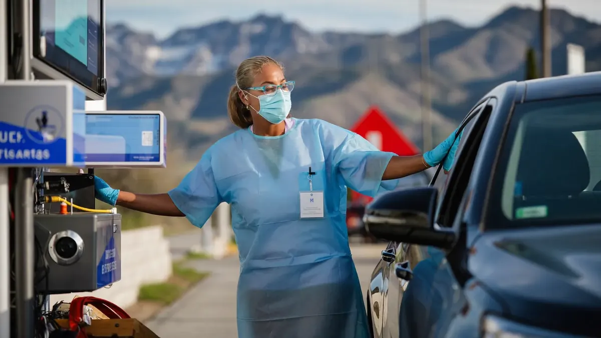 An adult patient at a Colorado urgent care clinic reception desk with an insurance card, staff behind glass