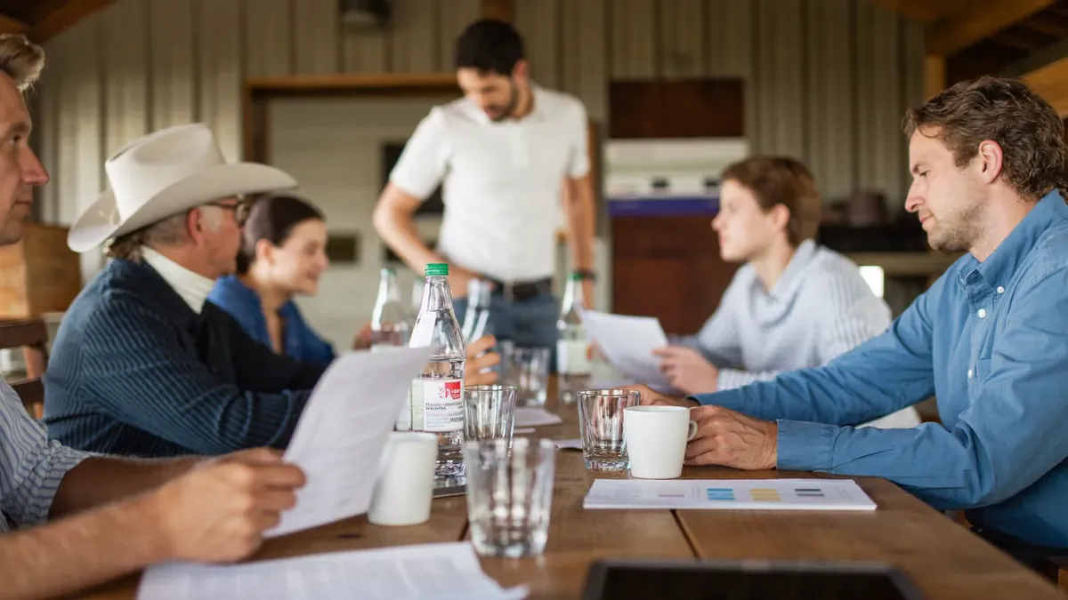 A small Colorado business team gathered around a conference table while an insurance advisor presents benefits options
