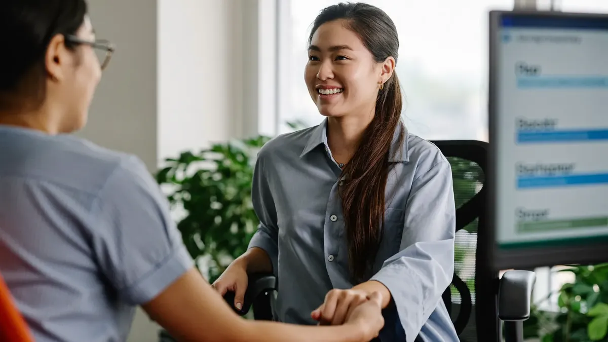A friendly young insurance advisor helping an adult client choose a health plan in a sunny Colorado office