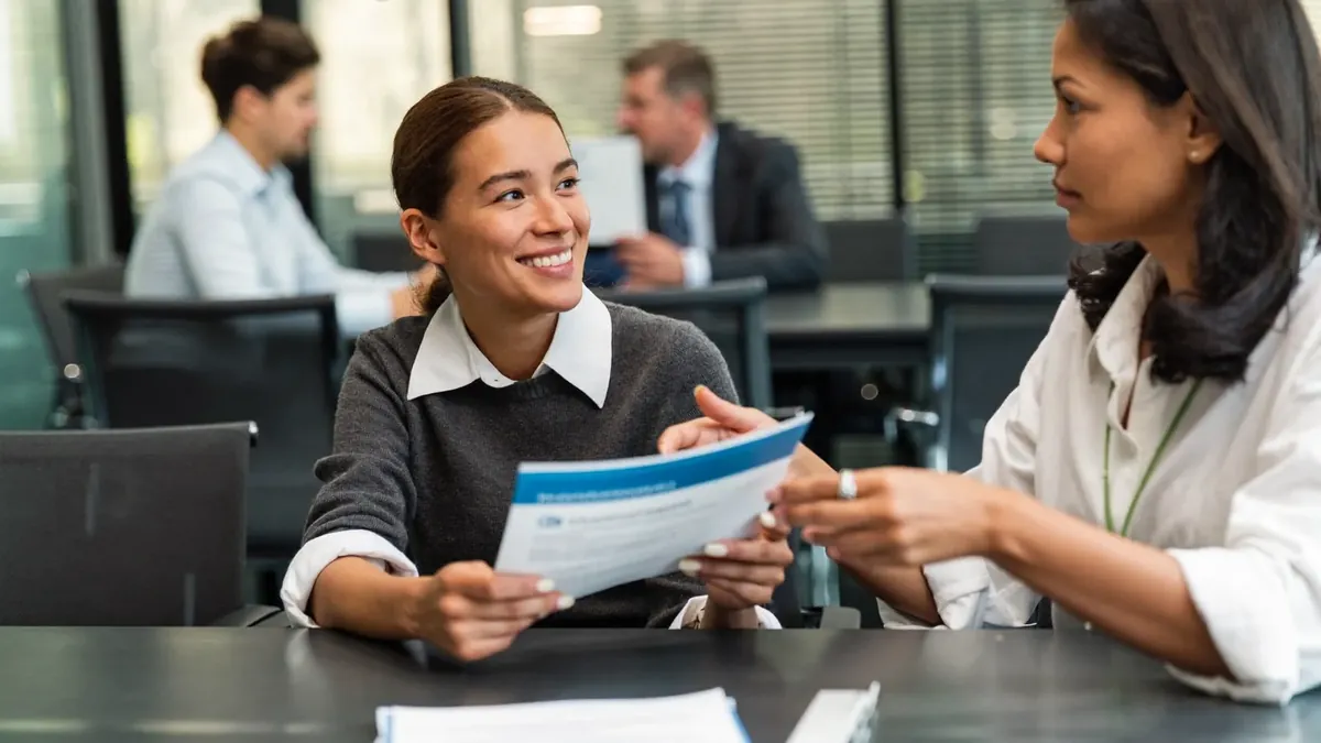A friendly young insurance advisor helping an adult client choose a health plan in a sunny Colorado office