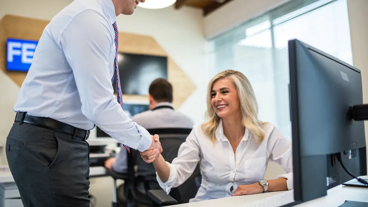 A young insurance broker shaking hands with an older client in a bright Broomfield, Colorado office