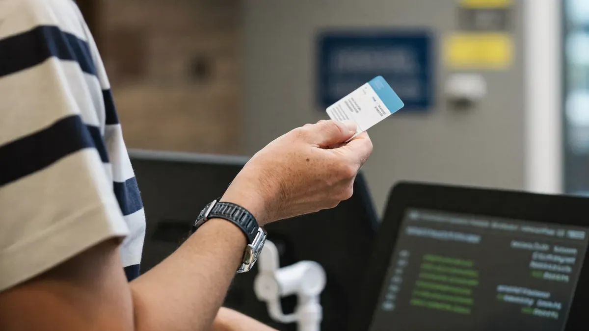 An adult patient at a Colorado urgent care clinic reception desk with an insurance card, staff behind glass