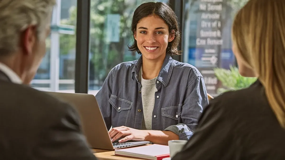 A young insurance professional studying licensing materials at a desk in a Denver co-working space, laptop and notes