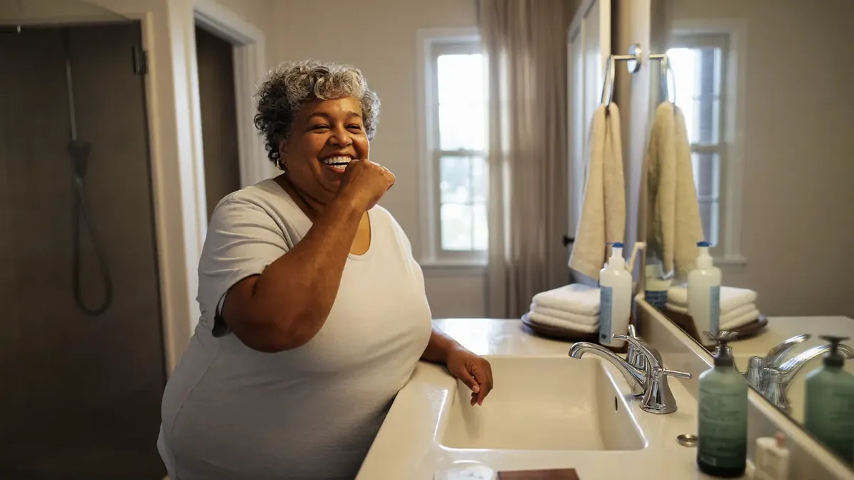 A smiling older adult in a bright modern Colorado dental office chair talking with a young dentist