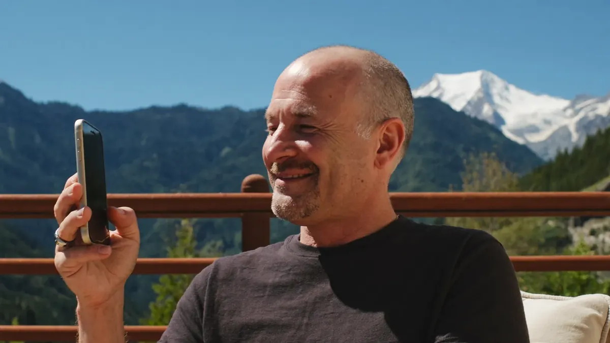 A man in his fifties completing an online life insurance application on his phone on a Colorado back deck